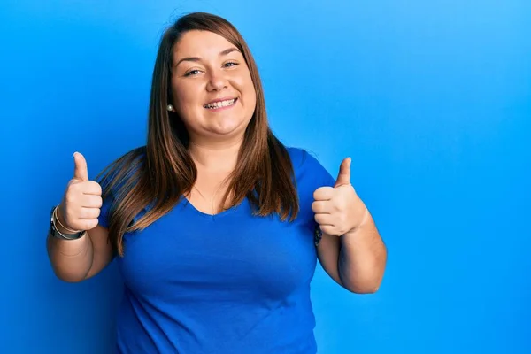 漂亮的黑发女人加上穿着休闲的蓝色T恤的女人 成功的标志着用手做着积极的手势 竖起大拇指笑了笑 快乐极了 快乐的表达和胜利的姿态 — 图库照片