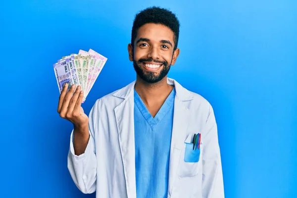 Hombre Hispano Guapo Con Barba Vistiendo Uniforme Médico Sosteniendo Rupia — Foto de Stock