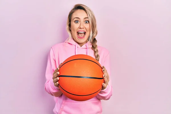 年轻美丽的金发女子举行篮球比赛庆祝疯狂和惊奇的成功 睁开眼睛尖叫兴奋 — 图库照片