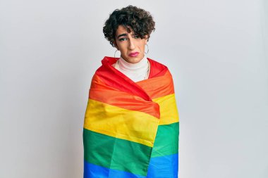 Gökkuşağı lgbtq bayrağına sarılı kadın makyajı yapan genç adam depresif ve endişeli, sinirli ve korkmuş. hüzünlü ifade. 