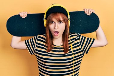 Kızıl saçlı, patenci, kulaklık takmış, kuşkucu ve iğneleyici bakışlı, ağzı açık bir şekilde şaşırmış genç bir kadın. 
