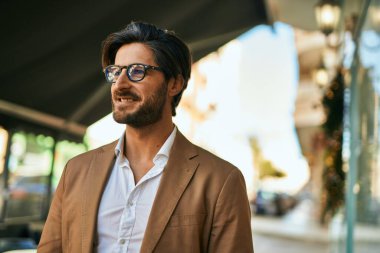 Genç İspanyol işadamı gülümseyerek şehirde mutlu mesut duruyor..