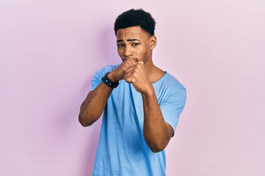 Afro-Amerikalı genç adam, günlük mavi tişört giyiyor. Yumruk savunma hareketleriyle dövüşmeye hazır. Kızgın ve üzgün. 