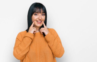 Gündelik kıyafetler giyen, ağzı açık gülümseyen, parmakları işaret eden ve neşeli gülümsemeye zorlayan genç İspanyol kadın. 