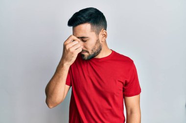 Günlük kıyafetler giyen genç İspanyol adam yorgun burnu ve gözleri ovuşturup yorgun ve baş ağrısı çekiyor. Stres ve hüsran kavramı. 