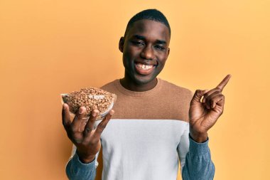 Genç Afro-Amerikan adam elinde mercimek kasesiyle gülümsüyor. 