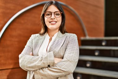 Genç İspanyol iş kadını şehirde çapraz hareketlerle mutlu gülümsüyor..