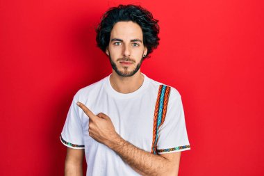 Parmaklarını yana doğru gösteren yakışıklı İspanyol adam yüzünde ciddi bir ifadeyle rahatlamış. Basit ve doğal bir şekilde kameraya bakıyorsun.. 