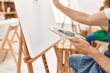 Sanat atölyesinde palet ve boya fırçası kullanarak orta yaşlı silah resimleri..