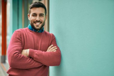 Genç İspanyol adam gülümseyerek şehirde mutlu mesut dikiliyor..