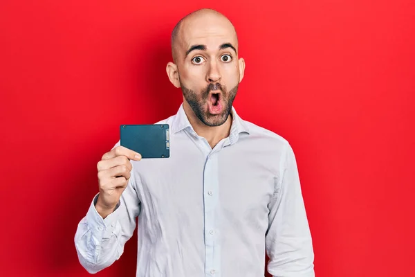 Young Bald Man Holding Ssd Memory Scared Amazed Open Mouth — Stock Photo, Image