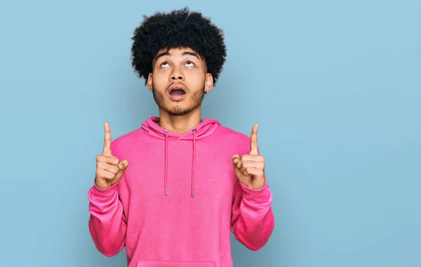 Joven Afroamericano Con Pelo Afro Vistiendo Sudadera Rosa Casual Asombrado —  Fotos de Stock