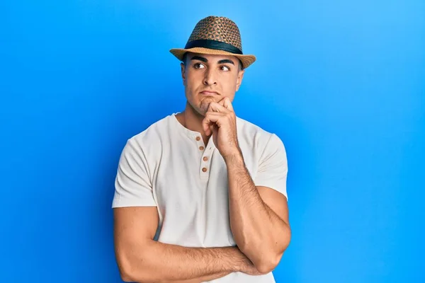 Ισπανόφωνος Νεαρός Άνδρας Που Φοράει Καλοκαιρινό Καπέλο Σοβαρό Πρόσωπο Σκεπτόμενος — Φωτογραφία Αρχείου