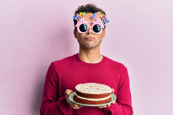 Przystojny Latynos Śmiesznych Urodzinowych Okularach Trzymający Tort Sceptyczny Nerwowy Marszczący — Zdjęcie stockowe