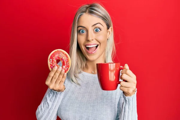 Hermosa Mujer Rubia Comiendo Donut Tomando Café Celebrando Loco Sorprendido —  Fotos de Stock