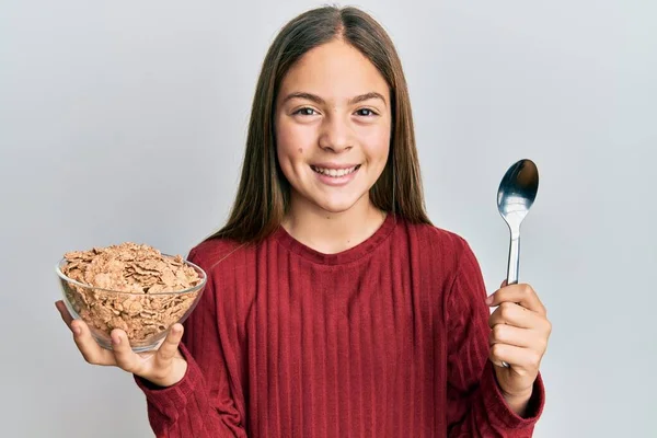 Krásná Brunetka Holčička Jíst Zdravé Celozrnné Cereálie Držet Lžíci Úsměvem — Stock fotografie