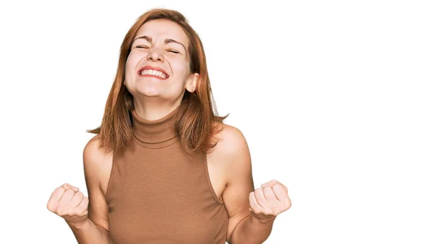 若い白人女性は非常に満足し 腕を上げて勝者のジェスチャーを行う興奮したカジュアル服を着て 笑顔と成功のために叫んで お祝いのコンセプト — ストック写真