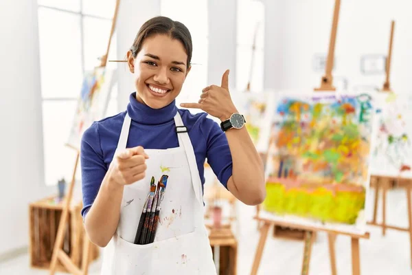 Joven Morena Estudio Arte Sonriendo Hablando Por Teléfono Señalándote Llámame —  Fotos de Stock