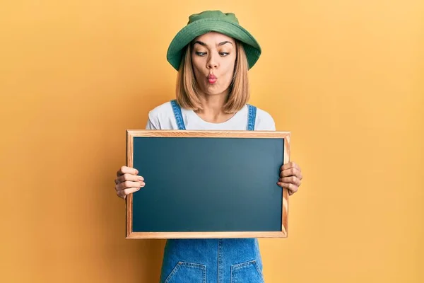 Young Caucasian Blonde Woman Holding Blackboard Making Fish Face Mouth — Stock Photo, Image