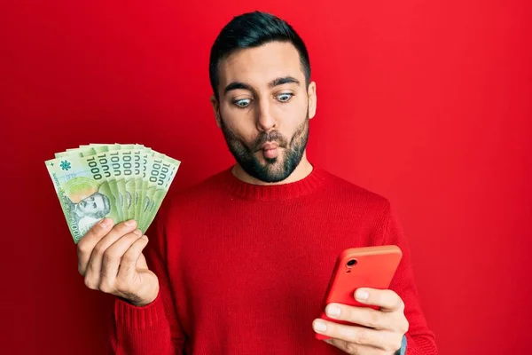 Young Hispanic Man Using Smartphone Holding Chilean Pesos Banknotes Making — Stock Photo, Image