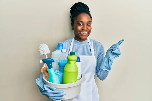 Mujer Afroamericana Con Pelo Trenzado Usando Delantal Sosteniendo Productos Limpieza —  Fotos de Stock