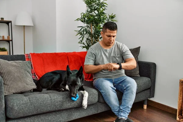 Jovem Latino Homem Cão Sentado Sofá Casa Verificando Tempo Relógio — Fotografia de Stock