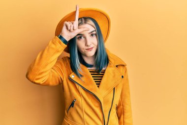 Sarı şapka ve deri ceket giyen genç modern bir kız. Alnında parmakları olan insanlarla alay ediyor. Ezik hareketler yapıyor, alay ediyor, hakaret ediyor.. 