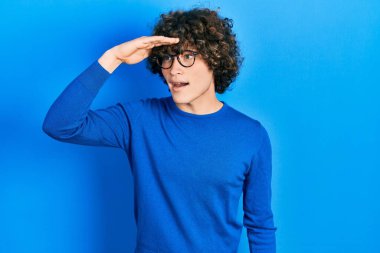 Yakışıklı, sıradan kıyafetler ve gözlük takan çok mutlu ve tebessüm eden bir genç. arama kavramı. 