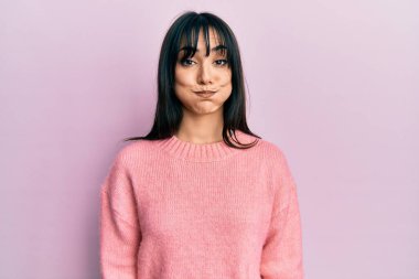 Kâküllü, kışlık süveter giyen esmer bir kadın komik yüzüyle yanaklarını şişiriyor. Havayla şişmiş ağız, çılgın bir ifade.. 