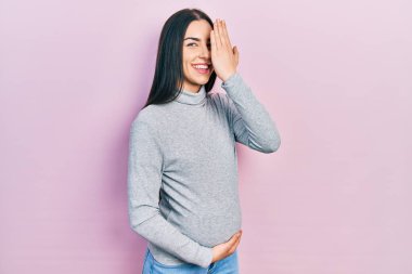 Mavi gözlü güzel bir kadın bebek bekliyor, hamile karnına dokunuyor bir gözünü eliyle kapatıyor, yüzünde kendine güvenen bir gülümseme ve sürpriz bir duygu var.. 