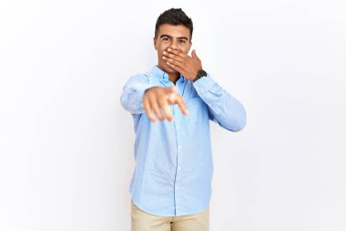 İş gömleği giyen genç İspanyol bir adam izole edilmiş arka planda duruyor. Sana gülüyor, kamerayı işaret ediyor, ağzı kapalı, utanç ifadesi takınıyor. 