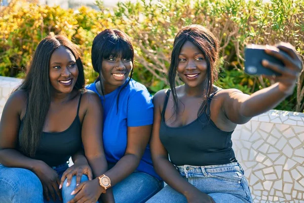 3人のアフリカ系アメリカ人の友人が公園でスマートフォンに笑顔で自撮り — ストック写真