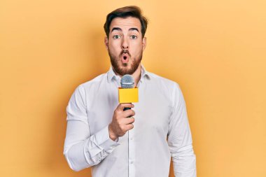 Sakallı yakışıklı beyaz adam mikrofon tutuyordu. Şaşırmak için ağzı açık kalmış, korkmuş ve hayrete düşmüştü. 