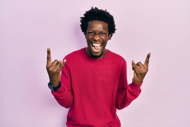 Sıradan kıyafetler giymiş, çılgın bir ifadeyle bağıran, elleri havada rock sembolü yapan genç bir Afrikalı Amerikalı. Müzik yıldızı. ağır müzik konsepti. 