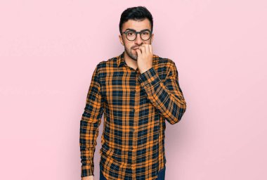 Sakallı, sıradan kıyafetler ve gözlüklü İspanyol bir adam. Ağzı tırnak yiyen elleri yüzünden gergin ve stresli görünüyor. anksiyete. 