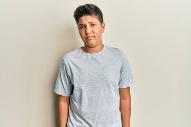 Gündelik gri tişört giyen genç İspanyol çocuk şüpheci ve gergin, sorun yüzünden surat asıyor. negatif kişi. 