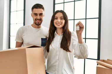 Genç İspanyol çift mutlu bir şekilde gülümsüyor. Karton kutular ve yeni evin anahtarı ellerinde..