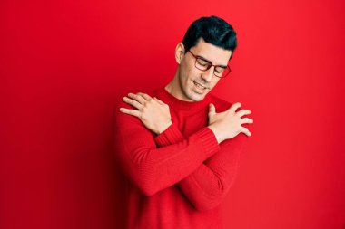 Yakışıklı İspanyol bir adam günlük kıyafetler ve gözlük takıyor mutlu ve pozitif, kendinden emin gülümsüyor. Sevgi ve özgüven. 