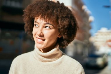 Genç İspanyol kız gülümseyerek şehirde mutlu mesut dikiliyor..