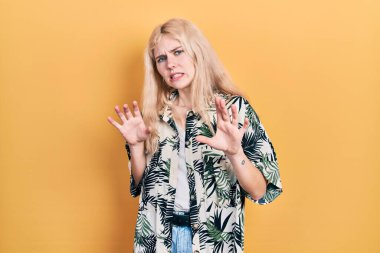 Sarı saçlı, tropikal tişört giyen güzel beyaz kadın tiksindirici ve tiksindirici bir ifade takınıyor çünkü tiksinti tepki veriyor. Eller havada. 