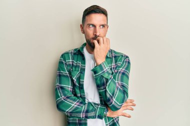 Sakallı, sıradan kıyafetler giyen, gergin ve ağzı tırnak yiyen yakışıklı bir adam. anksiyete. 