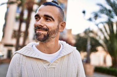 Sakallı yakışıklı orta yaşlı adam şehirde mutlu ve kendinden emin duruyor.