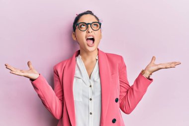 Güzel bir ortadoğulu kadın iş ceketi ve gözlük takıyor. Deli gibi bağırıyor, agresif bir ifadeyle bağırıyor ve kollarını kaldırıyor. hüsran kavramı. 