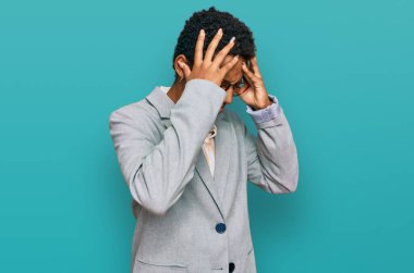 Genç Afro-Amerikalı kadın iş kıyafetleri giyiyor. Baş ağrısı ve stres yüzünden acı çekiyor. Ağrı ve migren yüzünden. Eller başının üstünde.. 