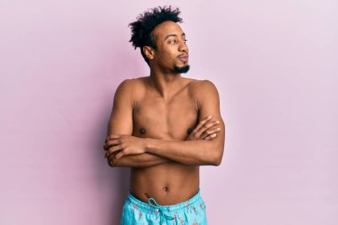 Sakallı, mayolu genç bir Afro-Amerikalı. Gülümsüyor, yan tarafa bakıyor ve düşünüyor.. 