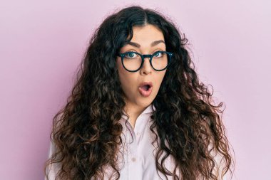 Kıvırcık saçlı, günlük kıyafetler ve gözlük takan genç esmer kadın. Şaşırtıcı bir ifade, korku ve heyecan dolu bir yüz ifadesiyle dehşete düşmüş ve şok olmuştu.. 