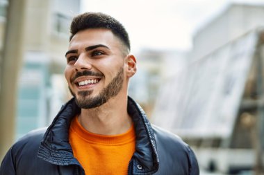 Yakışıklı, sakallı, neşeli ve kendine güvenen, kışlık palto giyen bir İspanyol.