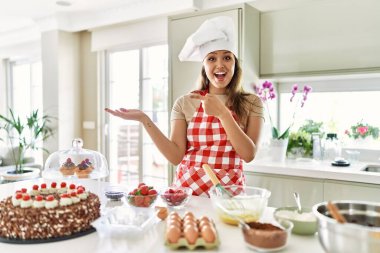 Güzel, genç, esmer pasta şefi kadın mutfakta hamur işleri pişirirken kameraya hayret ediyor ve gülümsüyordu.. 
