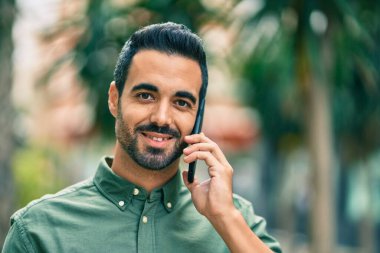 Genç İspanyol adam gülümsüyor. Şehirdeki akıllı telefondan konuşuyor..