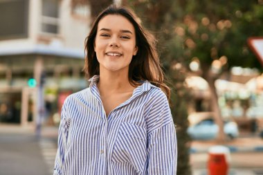 Genç İspanyol kız gülümseyerek şehirde mutlu mesut dikiliyor..